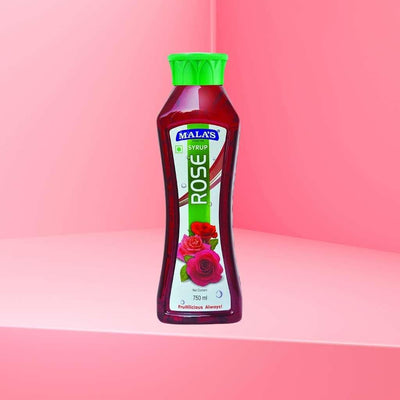 A bottle of Mala's Rose Syrup Rose petals floating in a glass of rose syrup